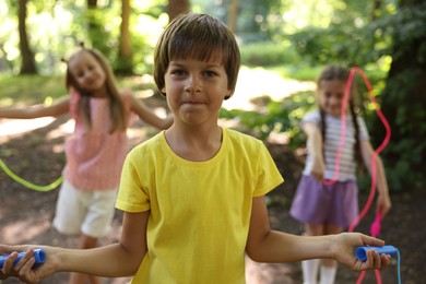 Photo of Cute little kids with jump ropes in park, selective focus