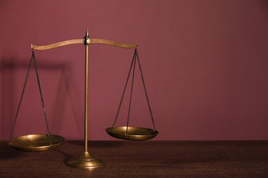 Photo of Scales of justice on table against dark background. Space for text