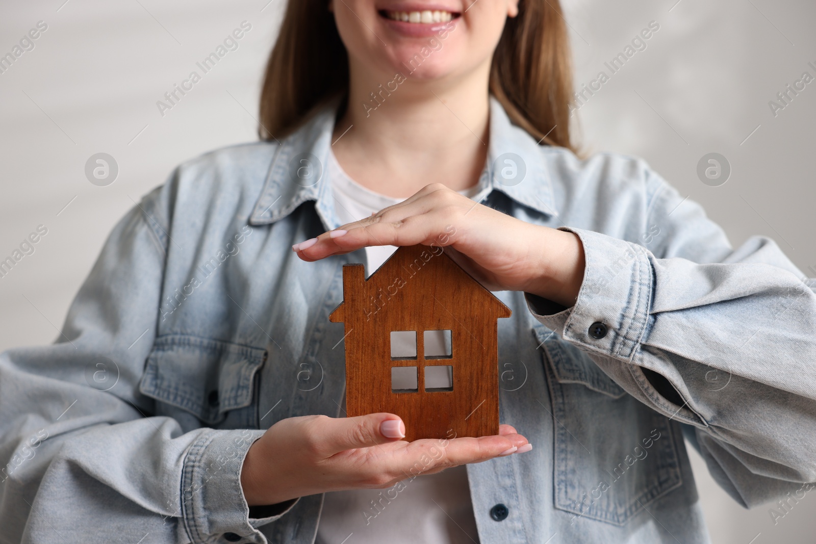 Photo of Home security. Woman with house figure on light background, closeup