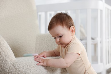 Photo of Cute little baby near armchair in room