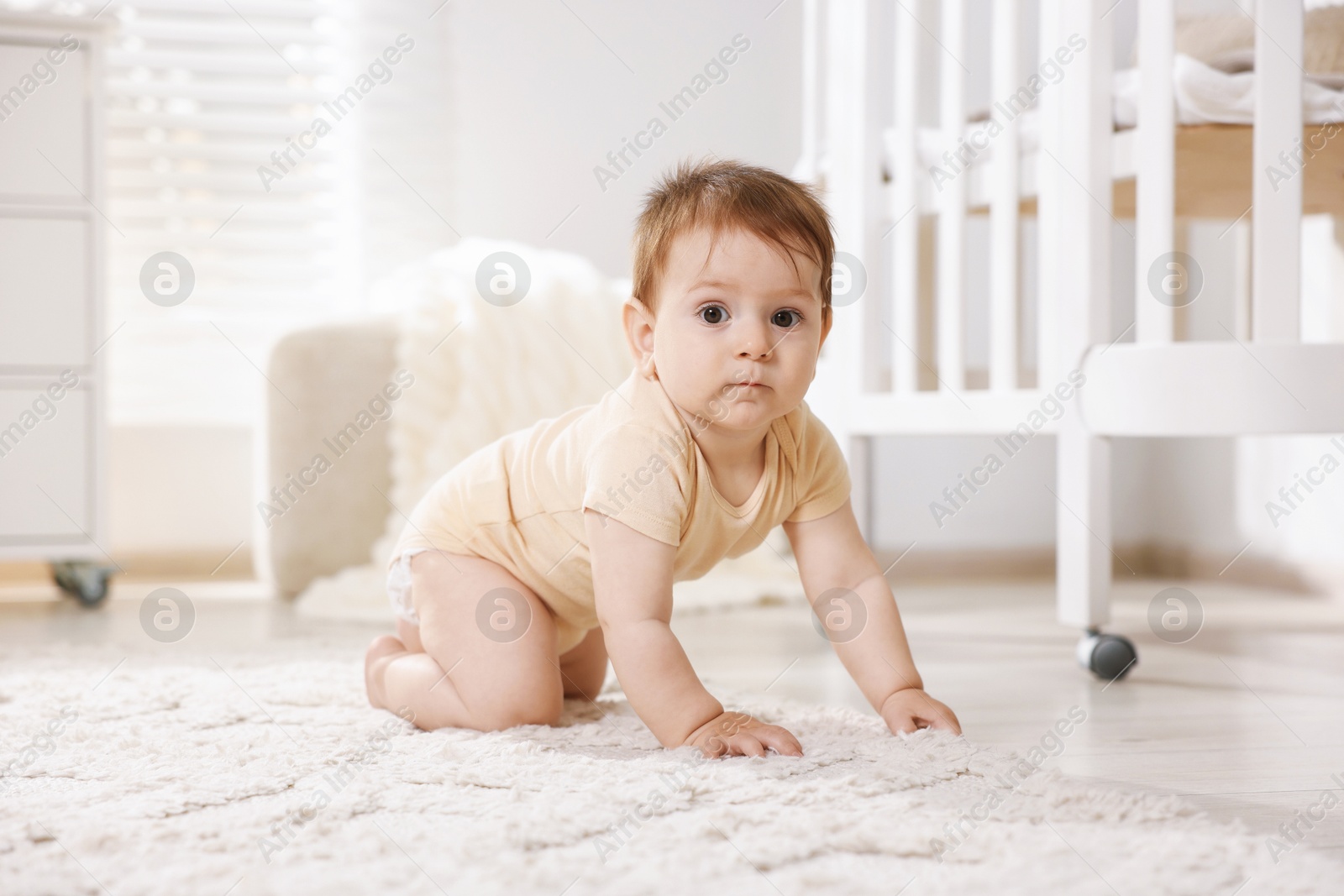Photo of Cute little baby crawling on floor in room