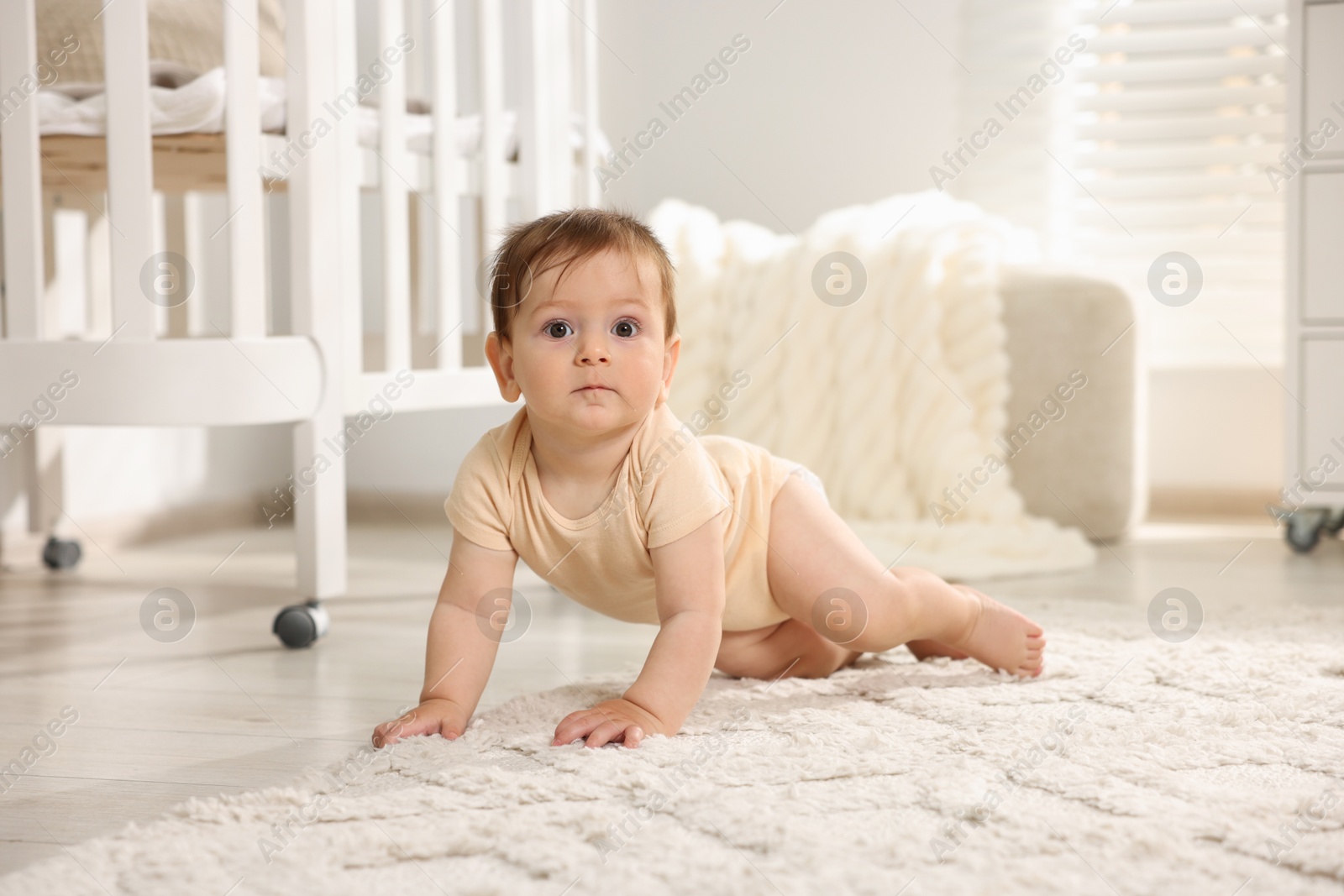 Photo of Cute little baby crawling on floor in room