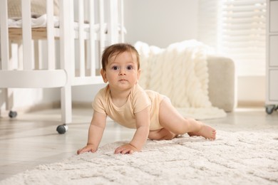 Photo of Cute little baby crawling on floor in room