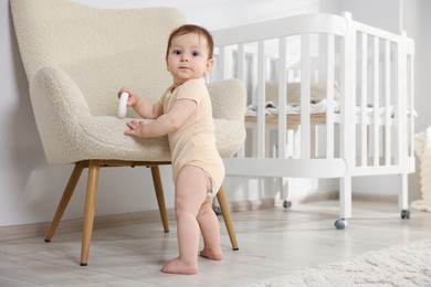 Photo of Cute little baby with toy near armchair in room