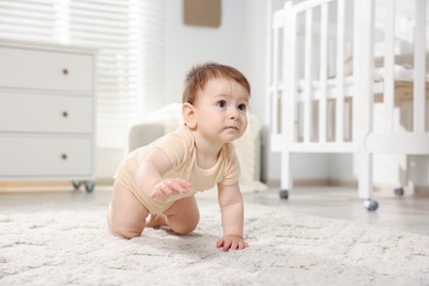 Photo of Cute little baby crawling on floor in room