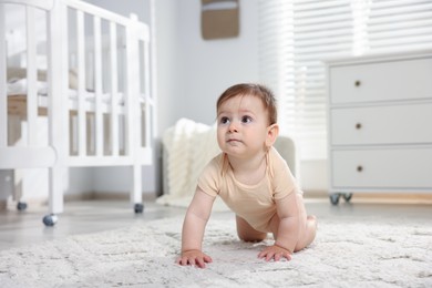 Photo of Cute little baby crawling on floor in room