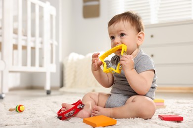 Photo of Cute little baby playing with toys in room