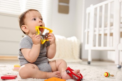 Photo of Cute little baby playing with toys in room. Space for text