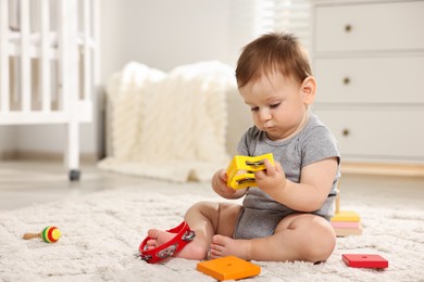 Photo of Cute little baby playing with toys in room. Space for text