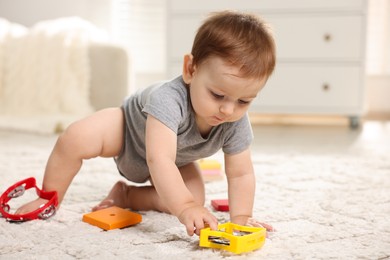 Photo of Cute little baby playing with toys in room