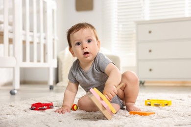 Photo of Cute little baby playing with toys in room