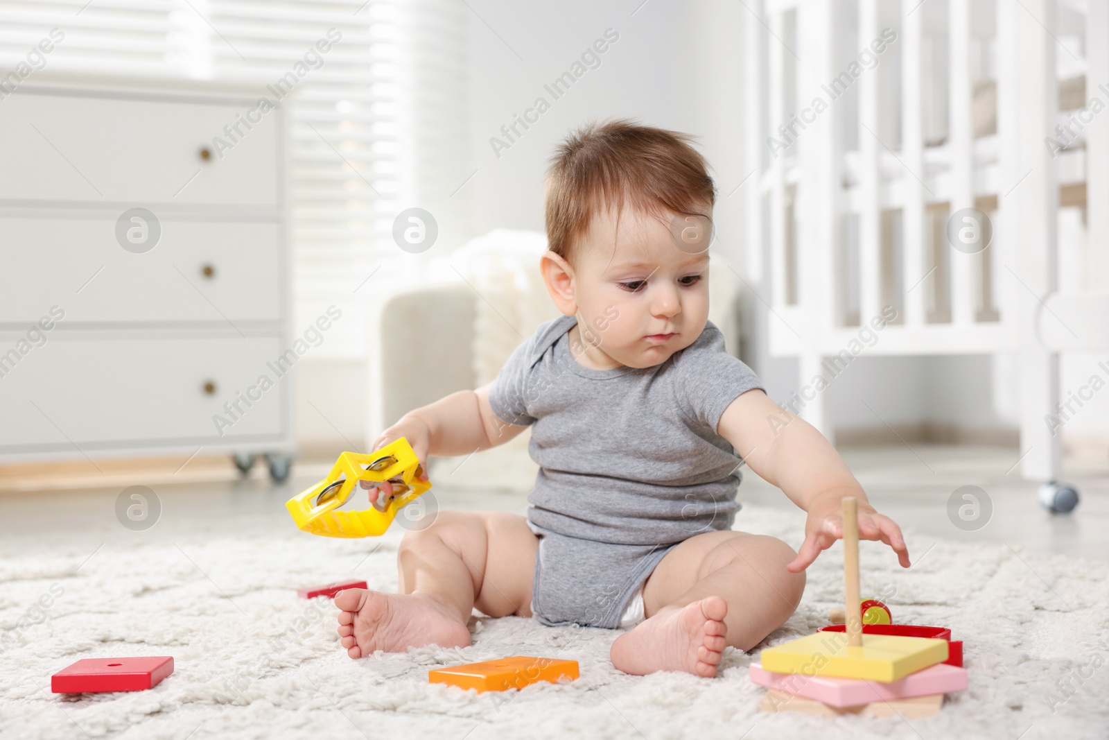 Photo of Cute little baby playing with toys in room