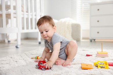 Photo of Cute little baby playing with toys in room