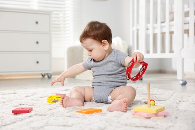 Photo of Cute little baby playing with toys in room