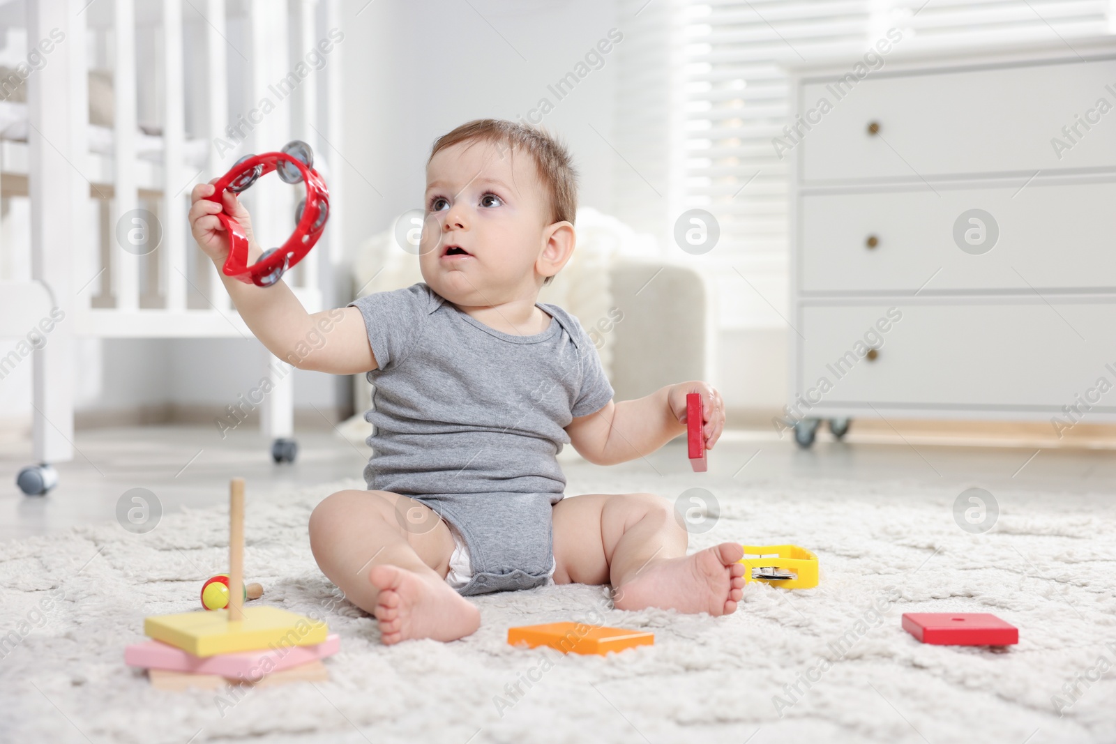 Cute little baby playing with toys in room. Space for text Photo of Cute little baby playing with toys in room. Space for text
