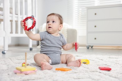 Photo of Cute little baby playing with toys in room. Space for text