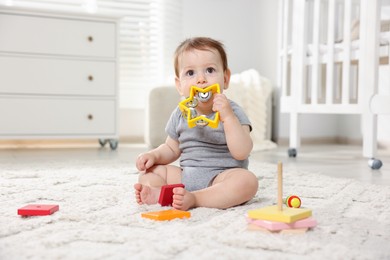 Photo of Cute little baby playing with toys in room