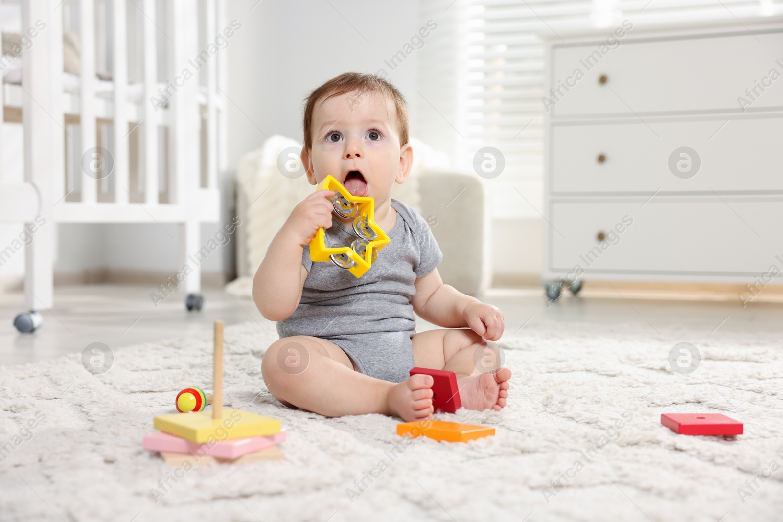 Photo of Cute little baby playing with toys in room