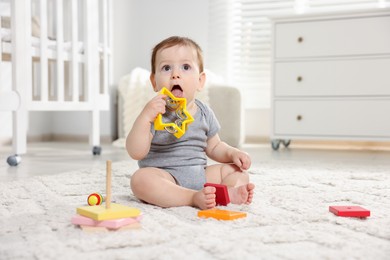 Photo of Cute little baby playing with toys in room