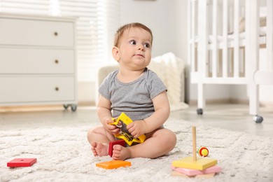 Photo of Cute little baby playing with toys in room