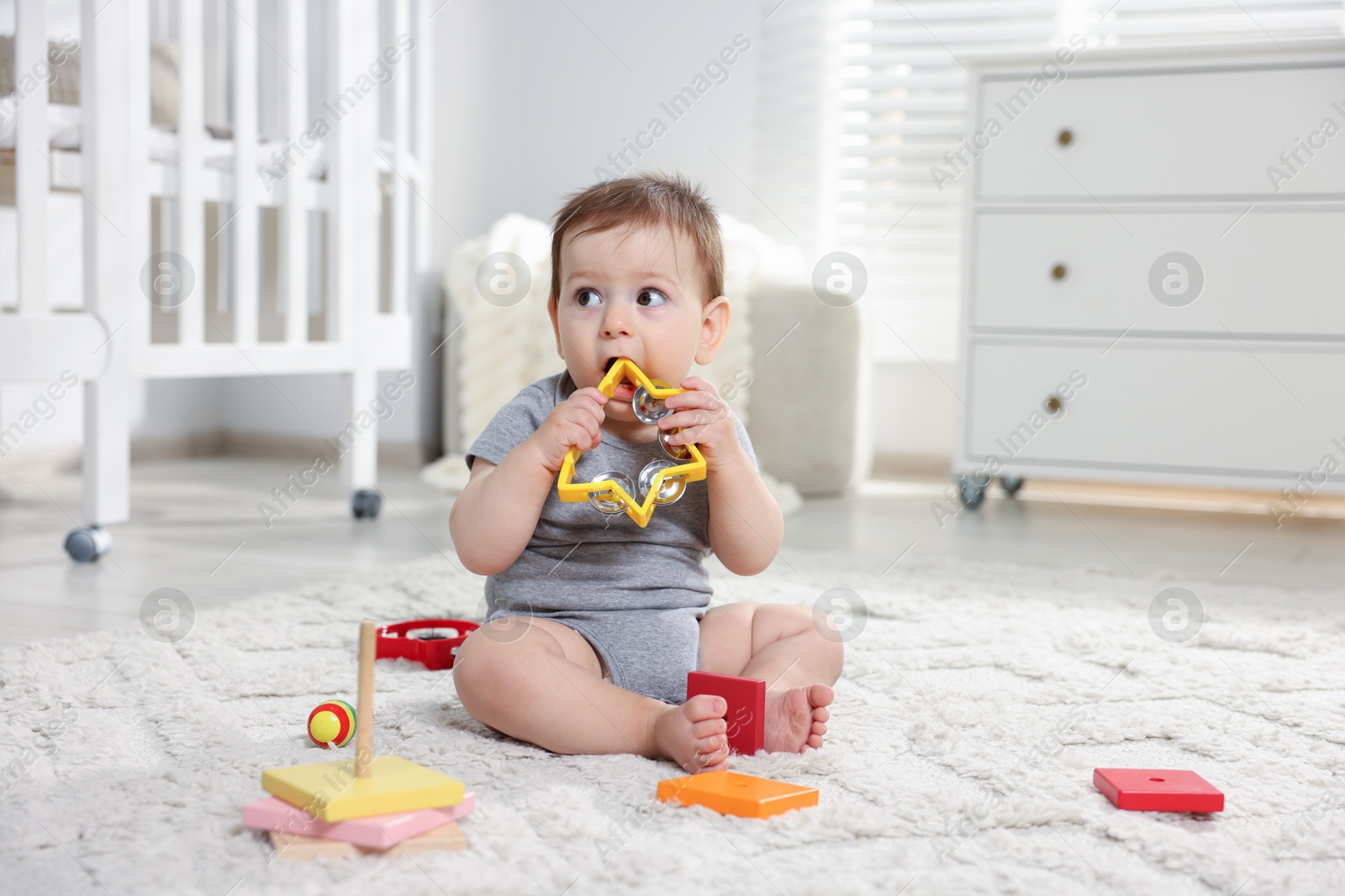 Photo of Cute little baby playing with toys in room