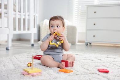 Photo of Cute little baby playing with toys in room