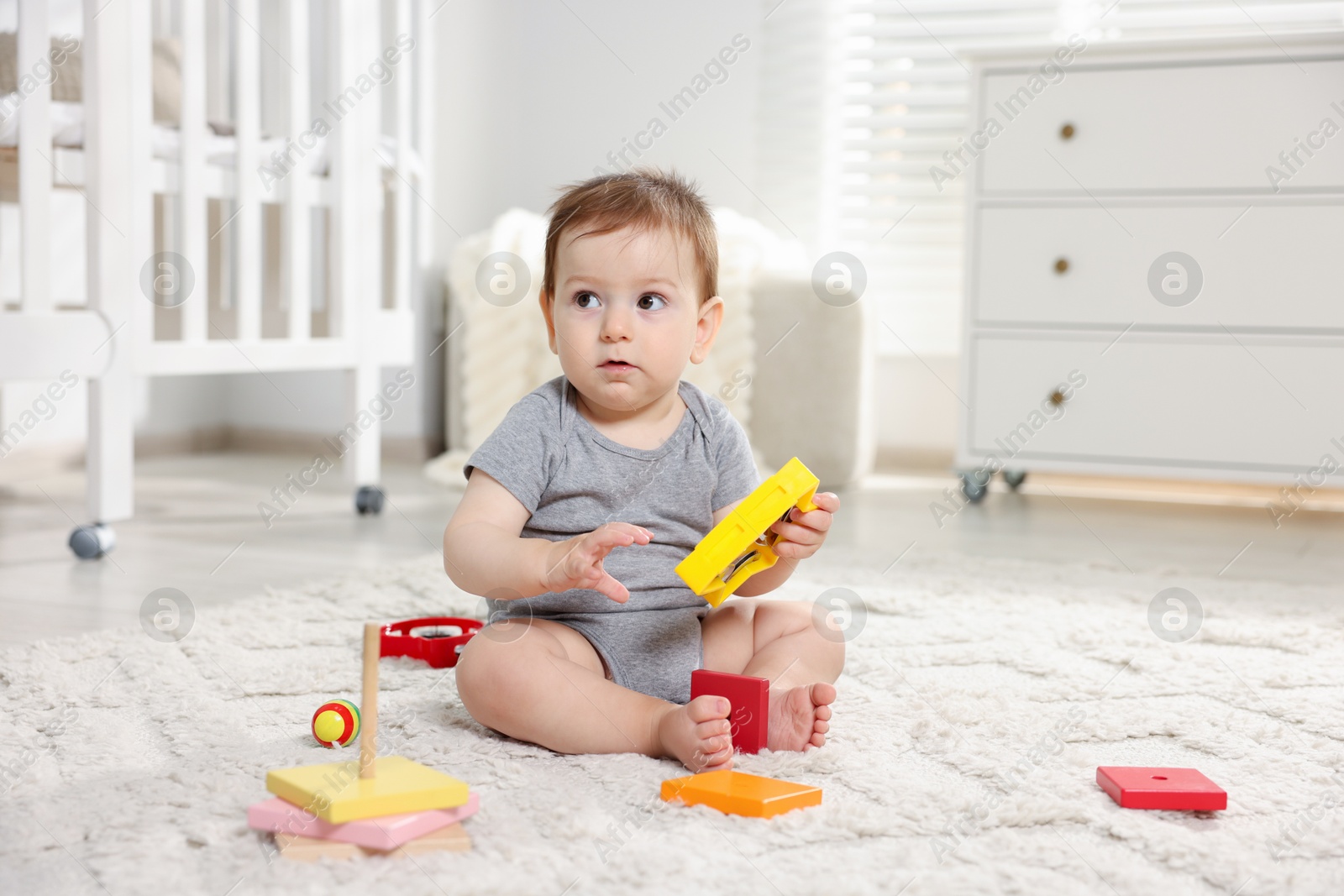Photo of Cute little baby playing with toys in room