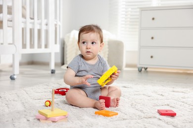 Photo of Cute little baby playing with toys in room