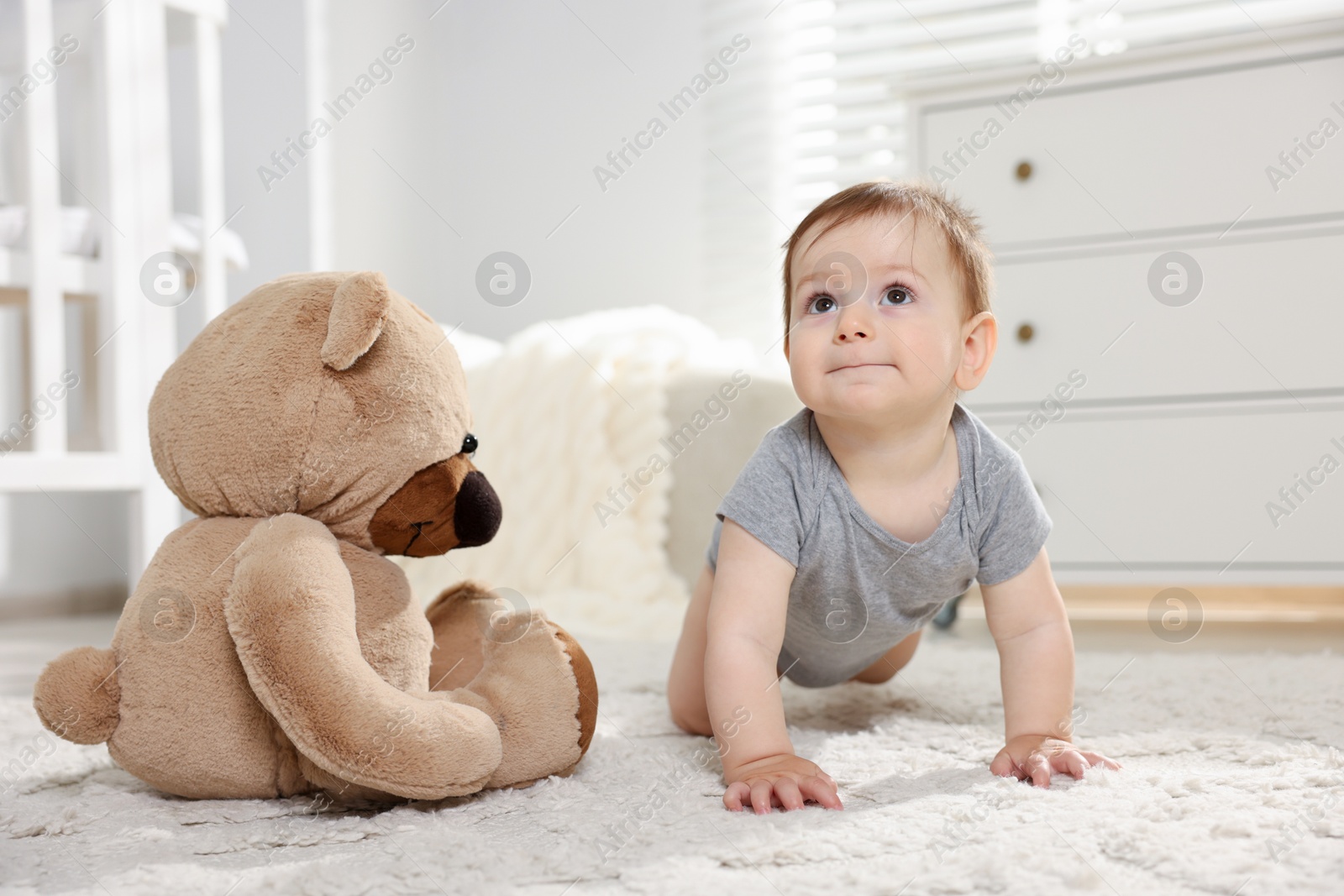 Cute little baby with teddy bear in room Photo of Cute little baby with teddy bear in room