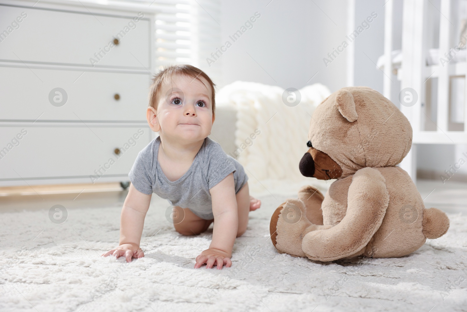 Cute little baby with teddy bear in room Photo of Cute little baby with teddy bear in room