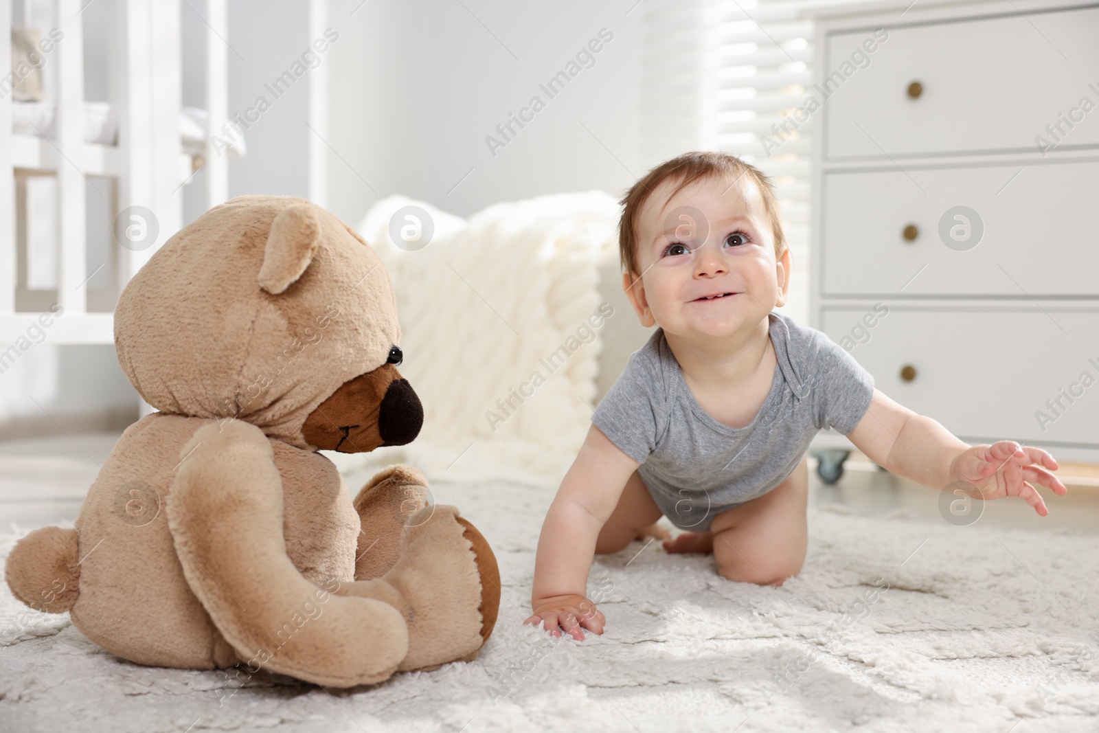 Cute little baby with teddy bear in room Photo of Cute little baby with teddy bear in room