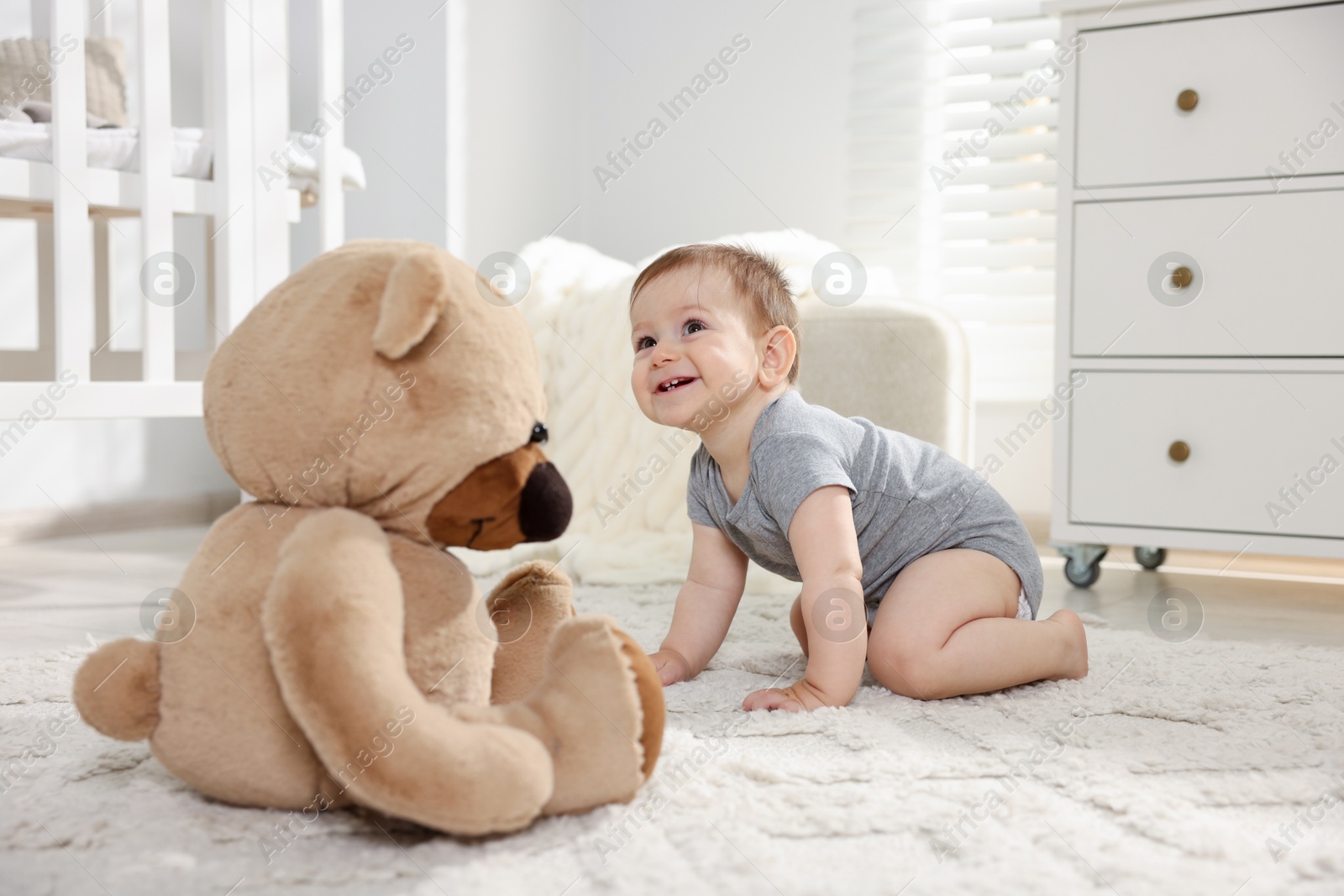 Cute little baby with teddy bear in room Photo of Cute little baby with teddy bear in room