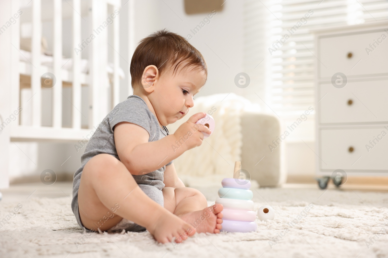 Photo of Cute little baby playing with toy pyramid in room. Space for text