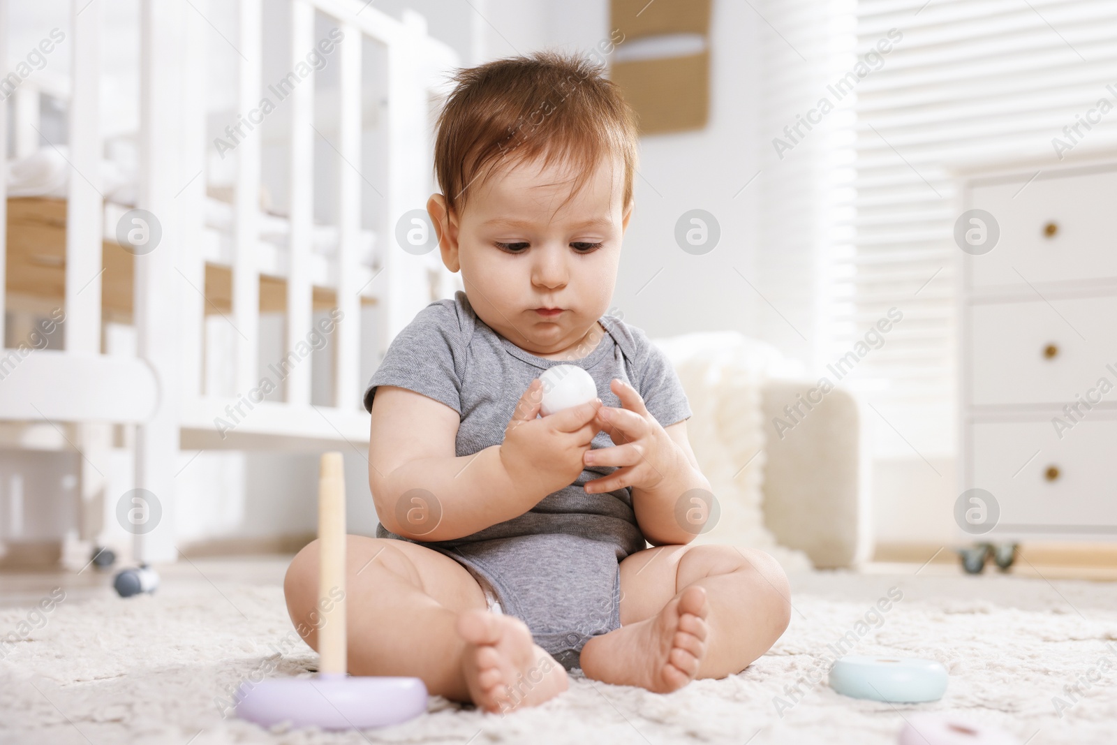 Cute little baby playing with toy pyramid in room Photo of Cute little baby playing with toy pyramid in room