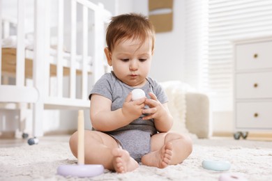 Photo of Cute little baby playing with toy pyramid in room