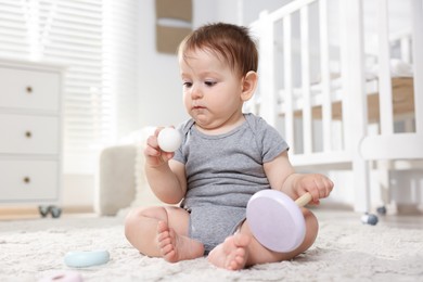 Photo of Cute little baby playing with toy pyramid in room