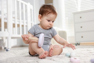 Photo of Cute little baby playing with toy pyramid in room