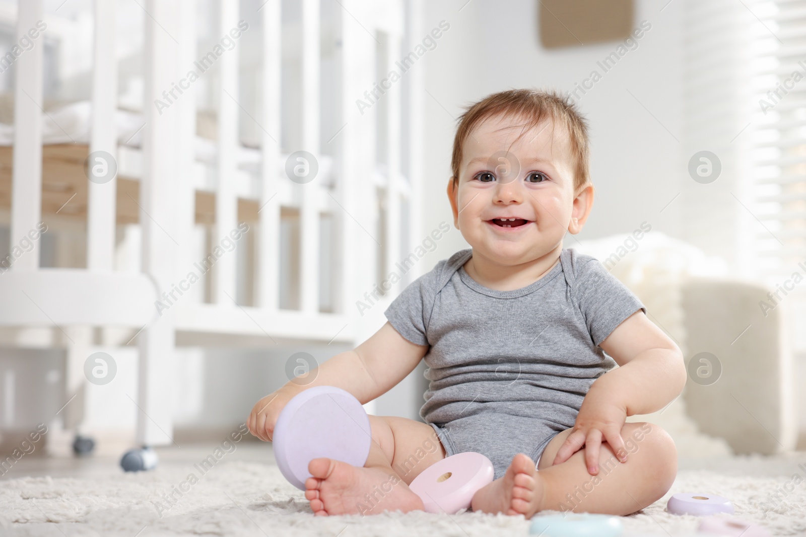 Cute little baby playing with toy pyramid in room. Space for text Photo of Cute little baby playing with toy pyramid in room. Space for text