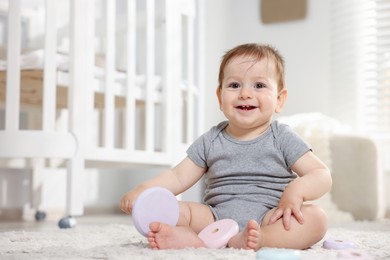 Photo of Cute little baby playing with toy pyramid in room. Space for text