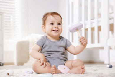Photo of Cute little baby playing with toy pyramid in room