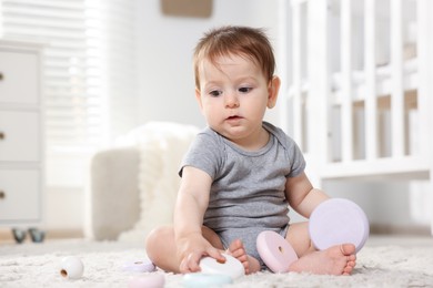 Photo of Cute little baby playing with toy pyramid in room