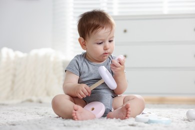 Photo of Cute little baby playing with toy pyramid in room
