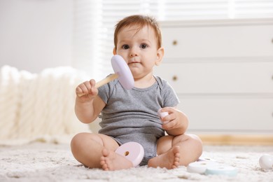 Photo of Cute little baby playing with toy pyramid in room