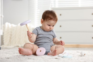Photo of Cute little baby playing with toy pyramid in room