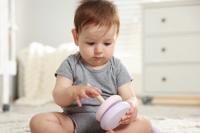 Photo of Cute little baby playing with toy pyramid in room