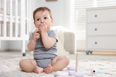 Photo of Cute little baby playing with toy pyramid in room. Space for text