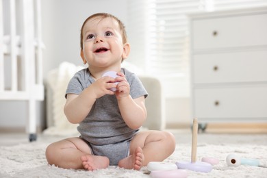Photo of Cute little baby playing with toy pyramid in room. Space for text