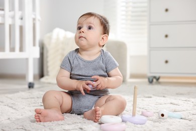 Photo of Cute little baby playing with toy pyramid in room