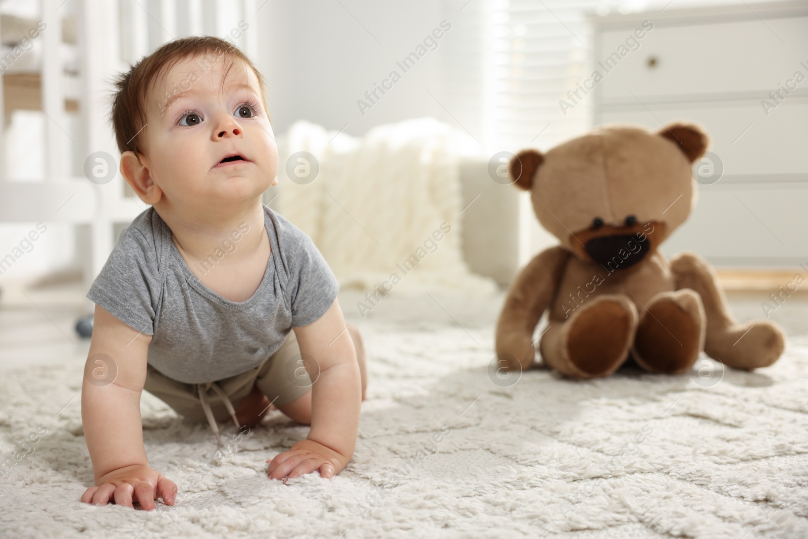 Photo of Cute little baby crawling on floor in room