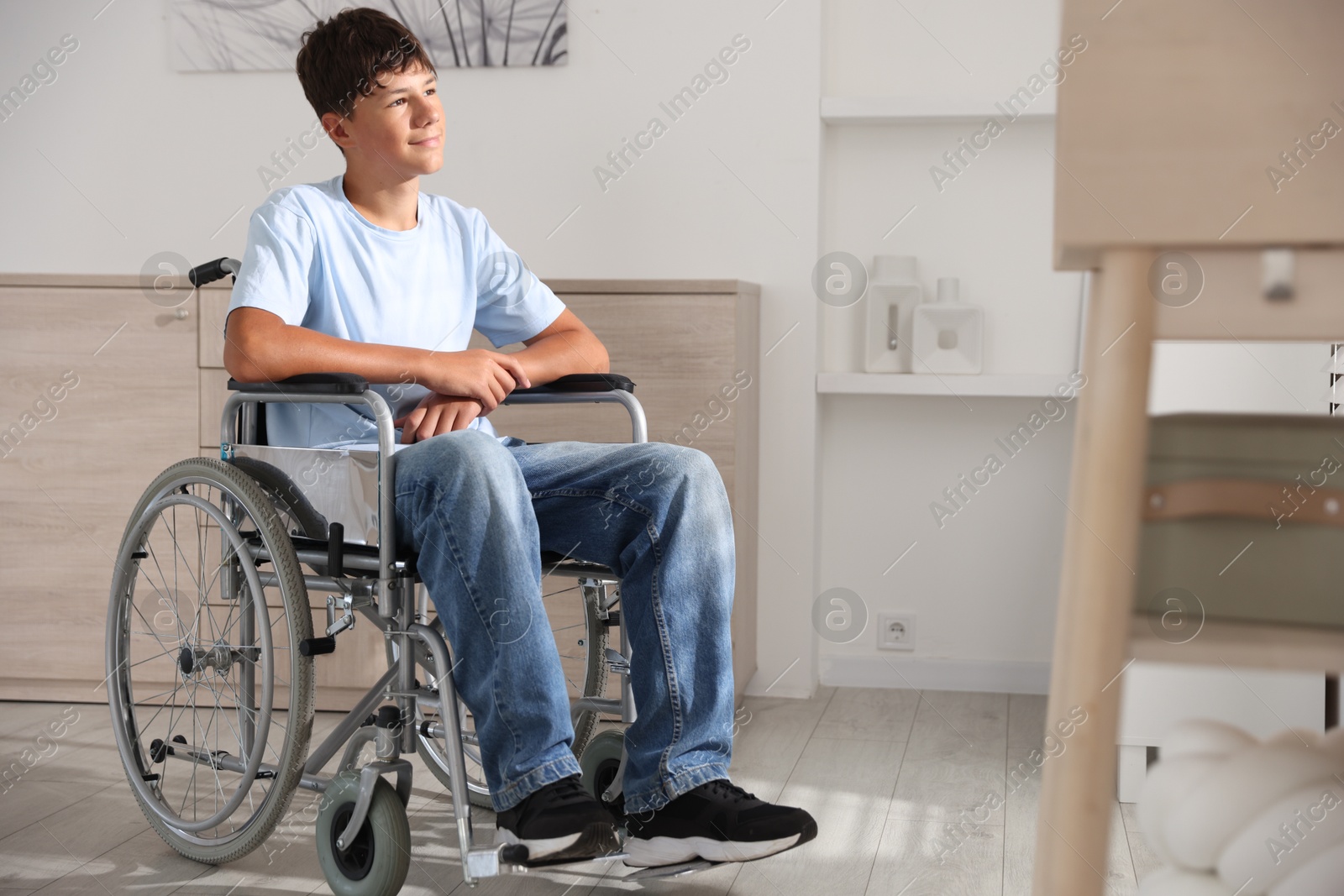 Photo of Happy teenage boy in modern wheelchair indoors, space for text